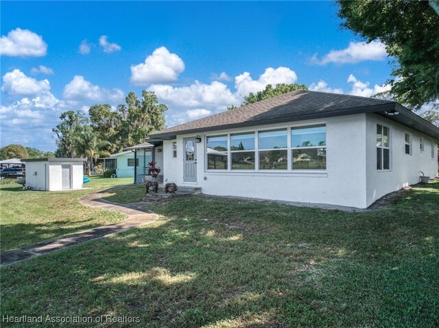 2 Chickasaw St, Lake Placid, FL 33852 - view of front of house with an outbuilding, stucco siding, a front yard, and roof with shingles