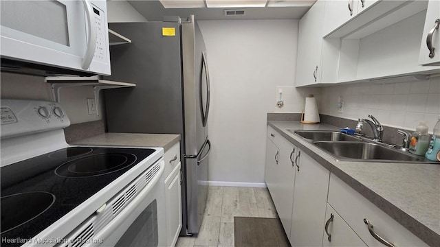 kitchen featuring decorative backsplash, white appliances, sink, light hardwood / wood-style flooring, and white cabinets