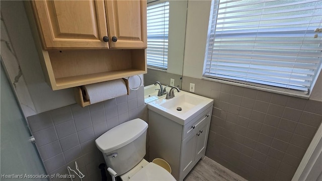 bathroom featuring vanity, toilet, and tile walls