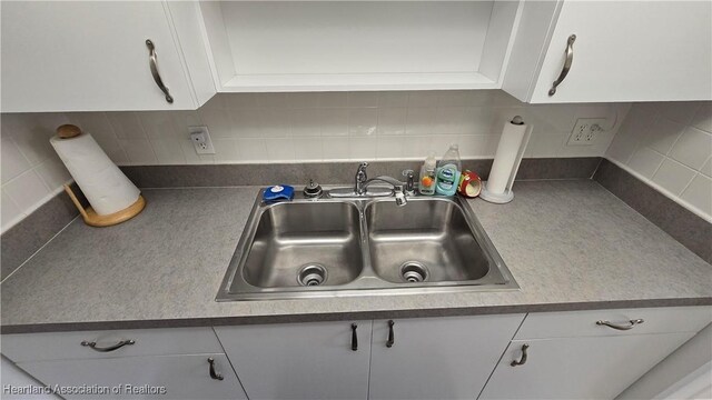 kitchen featuring white cabinets, backsplash, and sink