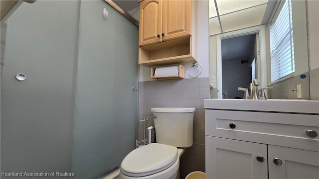 bathroom featuring vanity, tile walls, and toilet