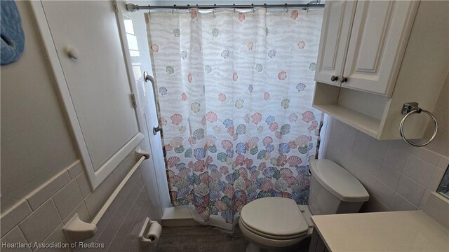 bathroom featuring a shower with shower curtain, vanity, toilet, and tile walls