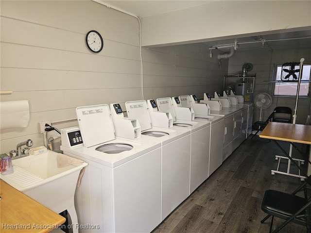 washroom with water heater, independent washer and dryer, sink, and dark wood-type flooring