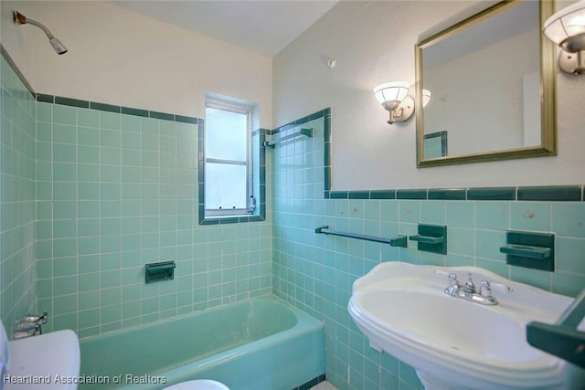 bathroom featuring tub / shower combination, a wainscoted wall, toilet, tile walls, and a sink