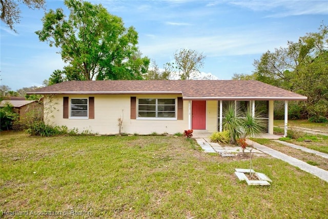 ranch-style home featuring roof with shingles and a front lawn