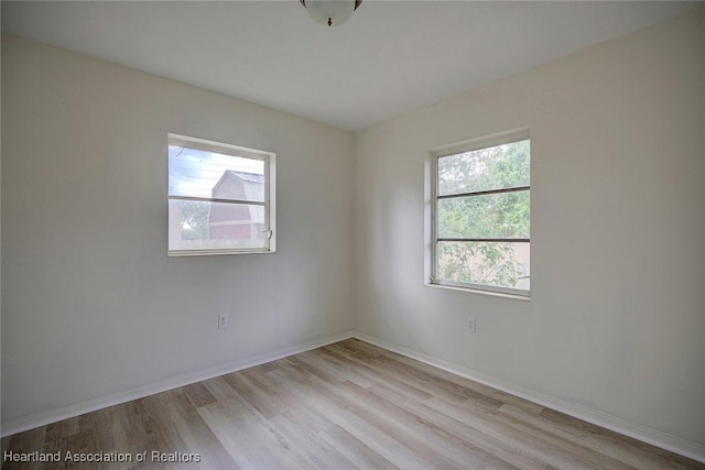 spare room featuring light wood-type flooring and baseboards