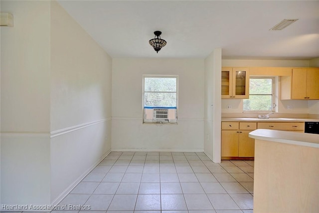 kitchen with visible vents, glass insert cabinets, light brown cabinetry, light countertops, and a sink