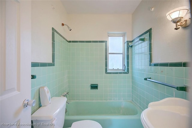 full bath with a wainscoted wall, toilet, tile walls, and bathing tub / shower combination