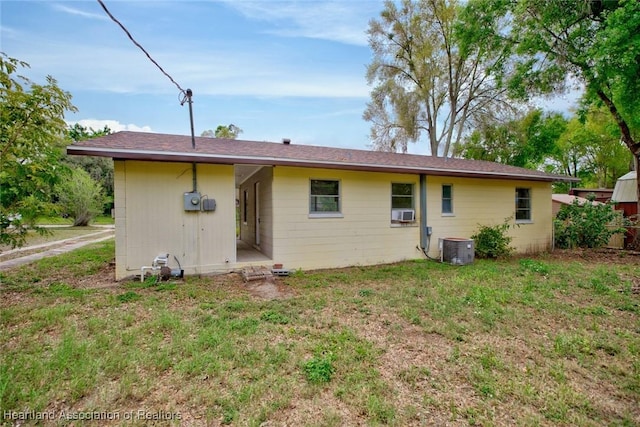 back of property with central air condition unit and a lawn