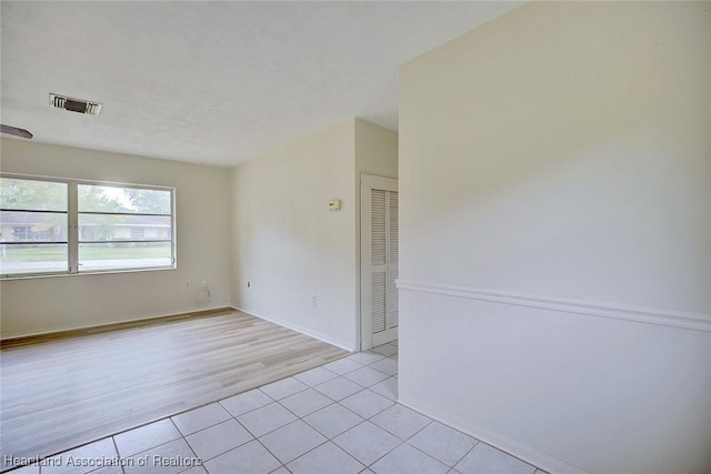 empty room featuring visible vents, baseboards, and light tile patterned flooring