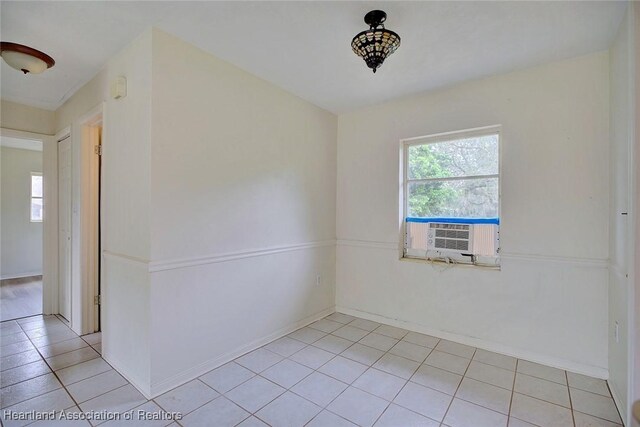 empty room with a wealth of natural light, cooling unit, baseboards, and light tile patterned flooring