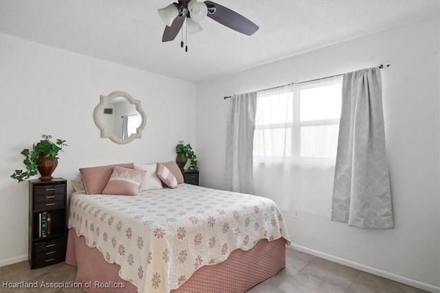 bedroom with light tile patterned floors, a ceiling fan, and baseboards