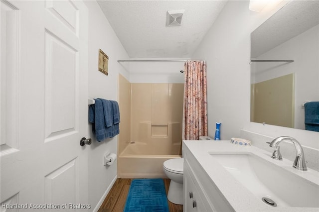 bathroom with vanity, wood finished floors, visible vents, a textured ceiling, and toilet