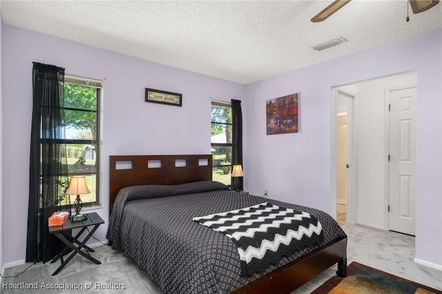 bedroom featuring a ceiling fan, baseboards, visible vents, carpet floors, and a textured ceiling