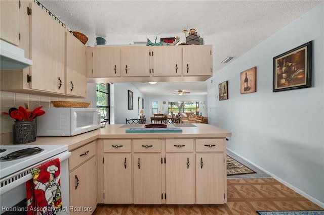 kitchen featuring light brown cabinetry, light countertops, a peninsula, white appliances, and a textured ceiling