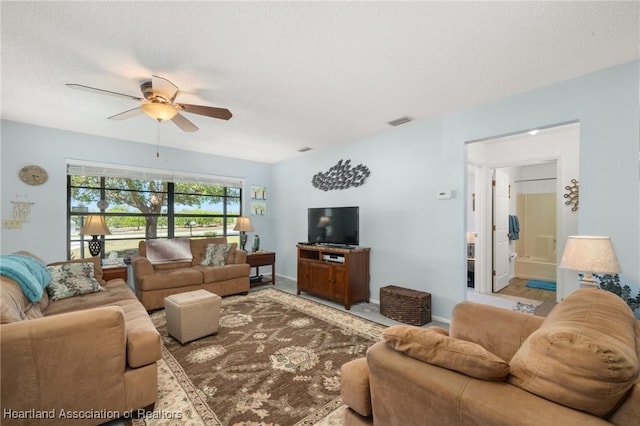 living area with baseboards, visible vents, a textured ceiling, and ceiling fan