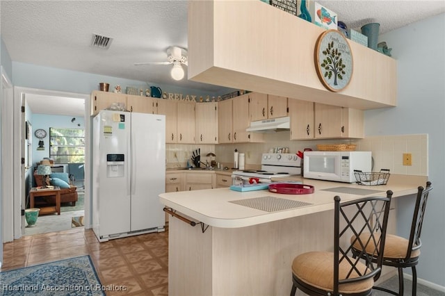 kitchen with white appliances, visible vents, a peninsula, light countertops, and under cabinet range hood