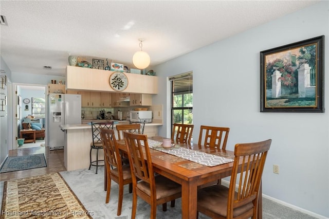 dining area with visible vents, light colored carpet, baseboards, and a textured ceiling