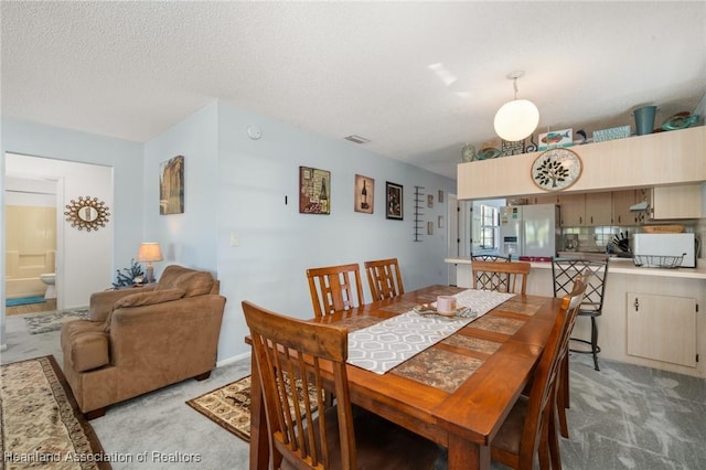 dining area featuring visible vents, light carpet, and a textured ceiling