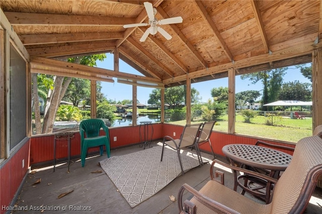 sunroom featuring a water view, a healthy amount of sunlight, ceiling fan, and vaulted ceiling