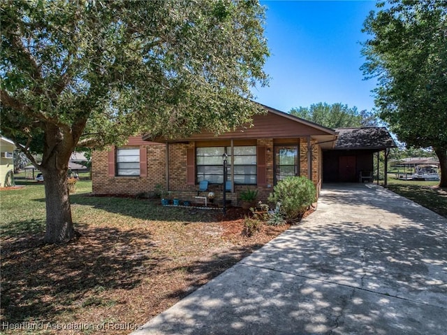 view of front facade with an attached carport, concrete driveway, brick siding, and a front lawn