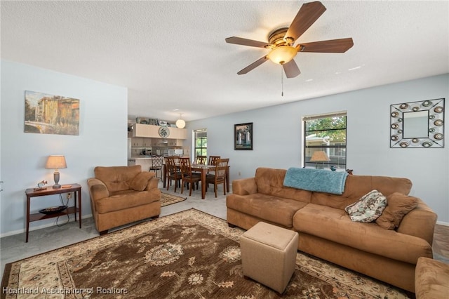 carpeted living area featuring a textured ceiling, plenty of natural light, baseboards, and ceiling fan