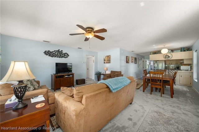 living room featuring lofted ceiling, a ceiling fan, visible vents, and light carpet