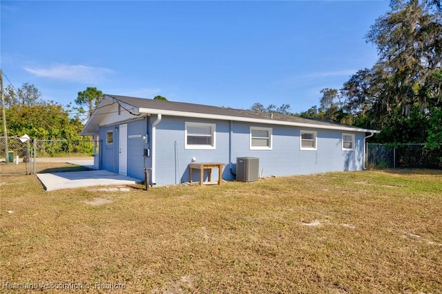 back of property with a yard, central AC, and a garage