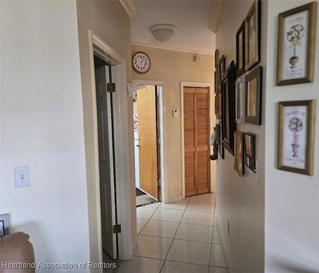 corridor featuring baseboards, crown molding, and light tile patterned flooring
