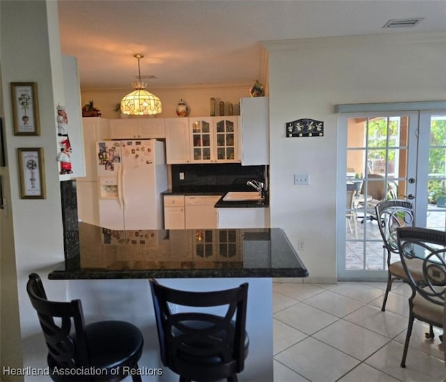 kitchen featuring a peninsula, visible vents, white cabinetry, decorative backsplash, and white appliances