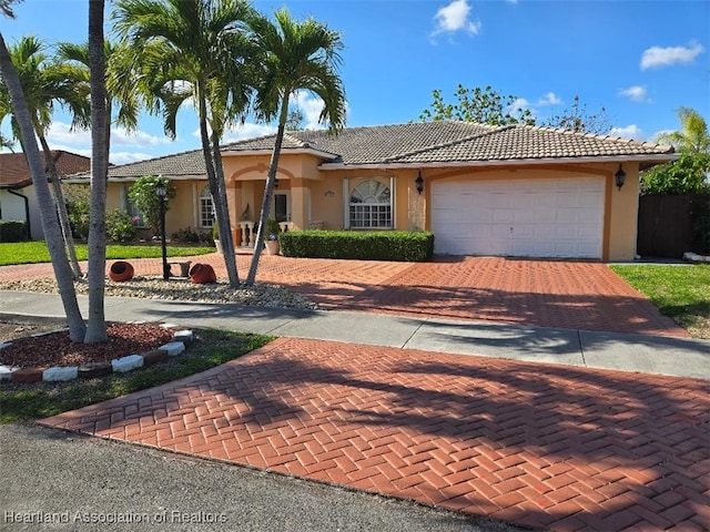 ranch-style home with a tile roof, stucco siding, and decorative driveway