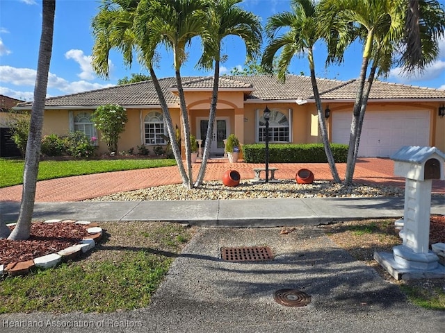 ranch-style home with a garage, driveway, a tiled roof, and stucco siding