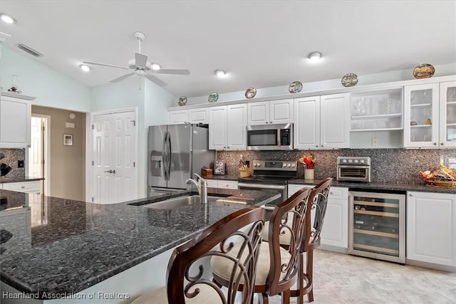 kitchen with vaulted ceiling, white cabinetry, appliances with stainless steel finishes, and wine cooler