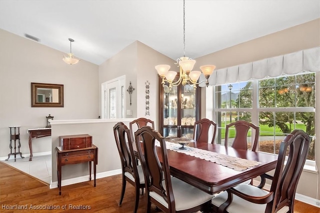 dining area featuring lofted ceiling, an inviting chandelier, and hardwood / wood-style floors