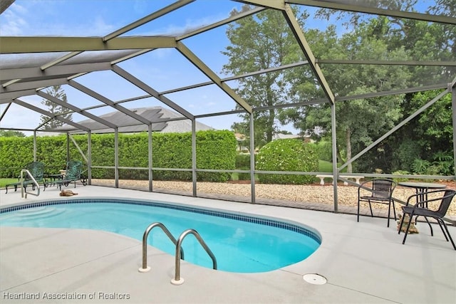 view of swimming pool featuring glass enclosure and a patio