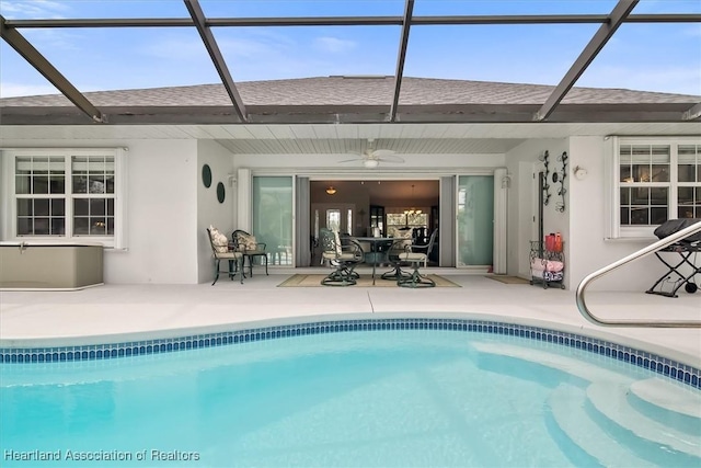 rear view of house featuring ceiling fan, glass enclosure, and a patio