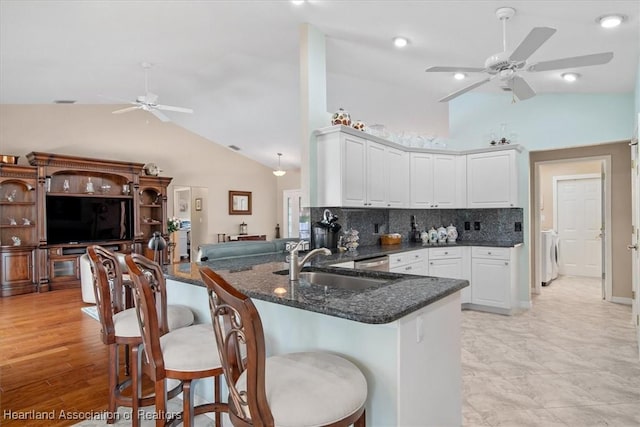 kitchen with white cabinets, washer / dryer, kitchen peninsula, and tasteful backsplash