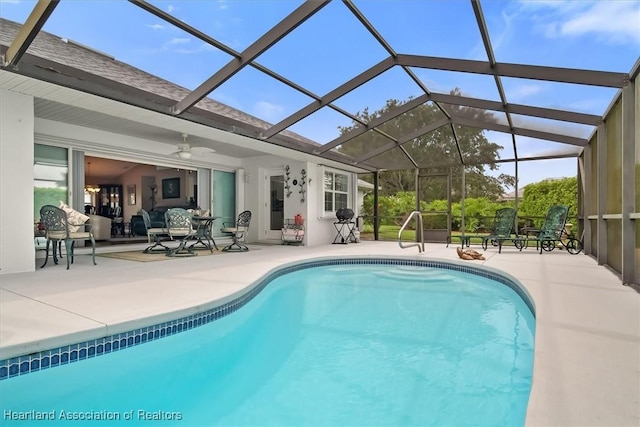 view of pool featuring glass enclosure, a patio area, and ceiling fan