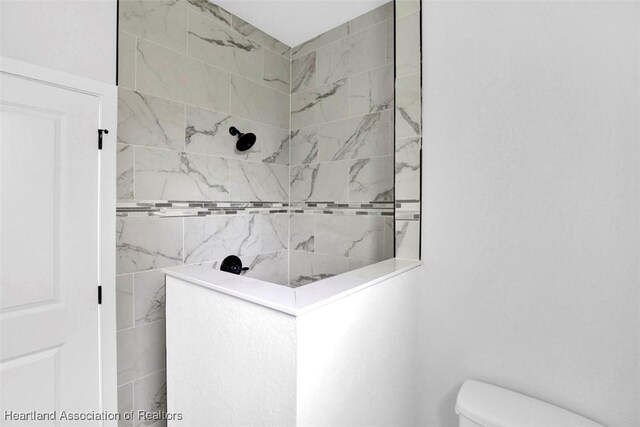 bathroom featuring a tile shower and toilet