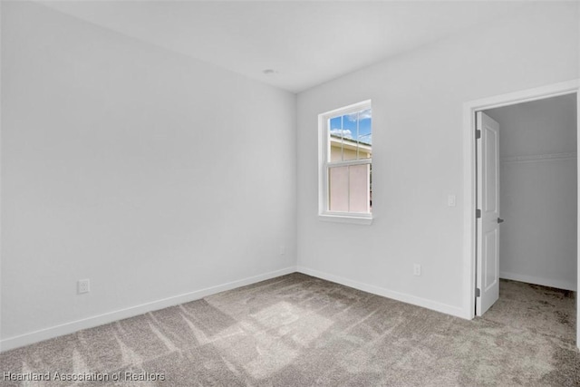 unfurnished bedroom featuring a spacious closet, a closet, and light colored carpet