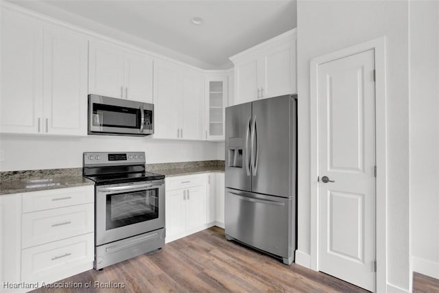 kitchen with wood-type flooring, light stone counters, white cabinetry, and stainless steel appliances