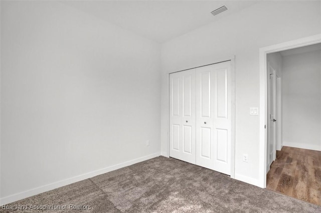 unfurnished bedroom with dark carpet and a closet