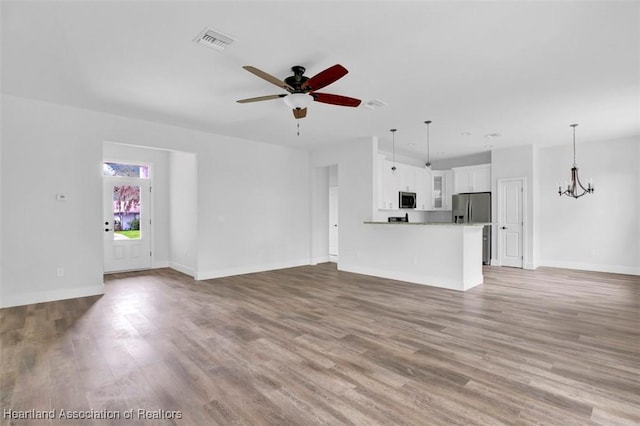 unfurnished living room featuring light hardwood / wood-style flooring and ceiling fan with notable chandelier