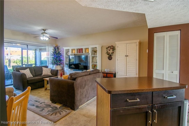 living room with ceiling fan, light tile patterned flooring, and a textured ceiling