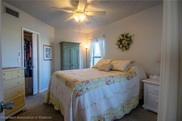 carpeted bedroom featuring ceiling fan, a closet, a spacious closet, and a textured ceiling