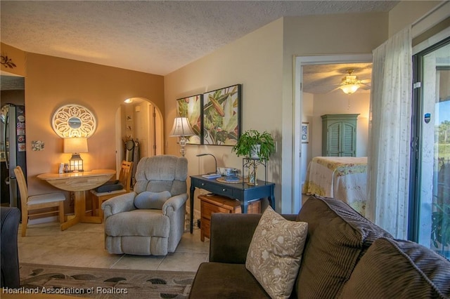 tiled living room featuring ceiling fan and a textured ceiling