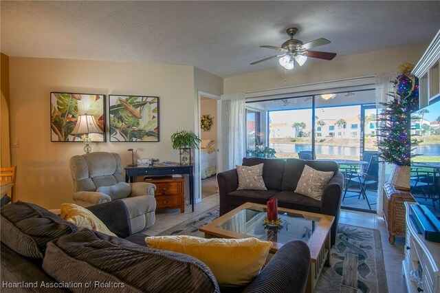 living room featuring ceiling fan and a textured ceiling