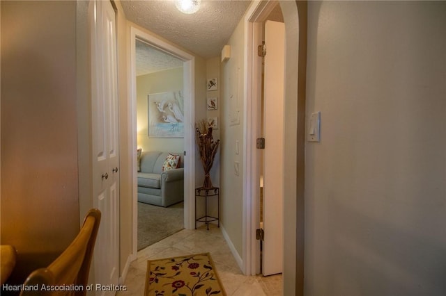 corridor featuring a textured ceiling and light tile patterned flooring