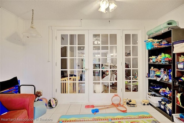 rec room with a textured ceiling, french doors, and tile patterned flooring