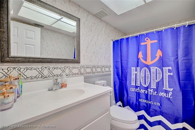 bathroom with curtained shower, toilet, and vanity